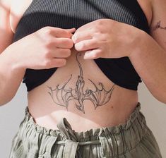 a woman is showing off her stomach tattoo