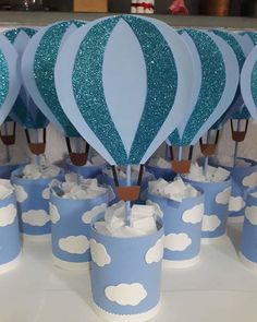 blue and white hot air balloons are on top of cupcakes in paper cups