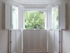 an open window with white shutters and wood flooring