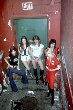 four women in red and black outfits posing for a photo inside an old jail cell