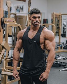 a man standing in front of a gym machine with his arms crossed and looking at the camera