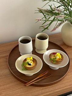 two plates with food on them sitting on a wooden table next to a cup of coffee