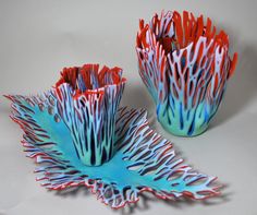 two red and blue vases sitting next to each other on a white table top