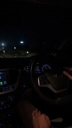 the interior of a car at night with its dashboard illuminated by blue lights and hands on the steering wheel