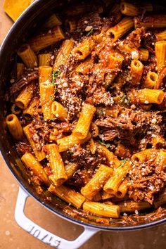 a pot filled with pasta and sauce on top of a table