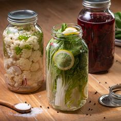 three jars filled with food sitting on top of a wooden table