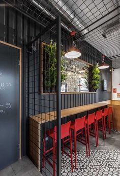 an empty restaurant with red chairs and black partitions on the wall, along with a chalkboard menu