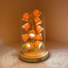 a glass dome filled with orange flowers on top of a wooden table next to a white wall