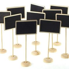 small black and white signs are lined up on wooden sticks with one sign in the middle