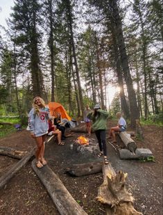 a group of people sitting around a campfire in the woods