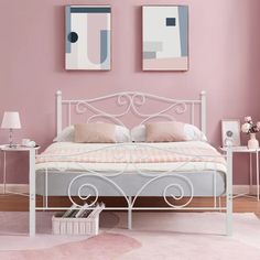 a bedroom with pink walls and white metal bed frame in front of two paintings on the wall