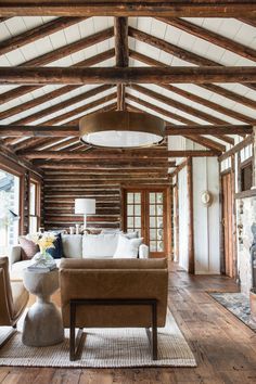 a living room filled with lots of furniture and wooden beams on the ceiling above a fire place