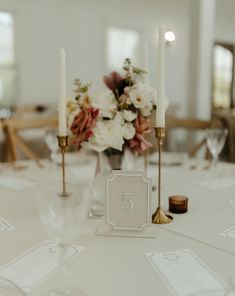 the table is set with candles, flowers and place cards for an elegant wedding reception