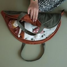 a person holding onto a purse with stuffed animals in it's bottom compartment,