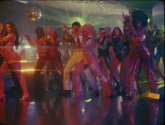 a group of people dancing on a dance floor with disco balls in the air behind them