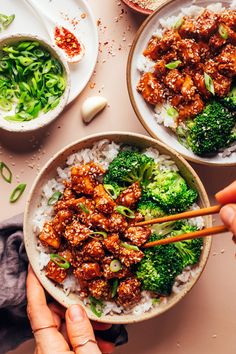 two bowls filled with meat and broccoli on top of rice next to chopsticks