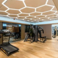 a gym with treadmills, exercise machines and other equipment in the room that is lit up