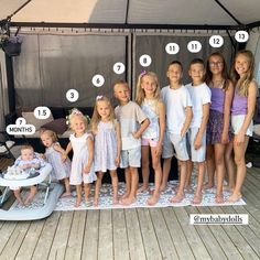 a group of children standing next to each other in front of a tent with numbers on it