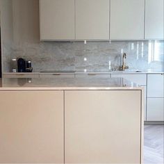 a kitchen with white cabinets and marble counter tops, gold faucet pulls on the cabinet doors