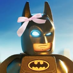 the lego batman movie character has glowing blue eyes and a pink bow on his head