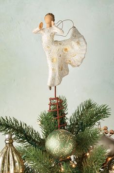 an angel figurine sitting on top of a christmas tree with ornaments around it