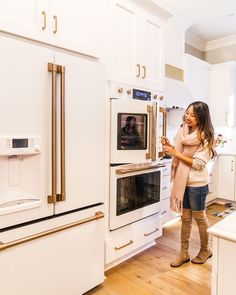 a woman standing in front of an oven with the door open and looking at her phone