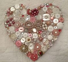 a heart made out of buttons on a bed