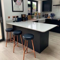 two stools sit at an island in the middle of a kitchen with blue cabinets