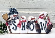 three snowmen with hats, scarfs and boots are sitting in front of a sign that says snow