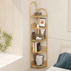 a gold shelf with books and pictures on it next to a bed in a room