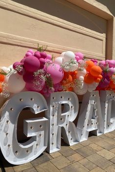 a large sign with balloons and flowers on it that says grand opening in front of a building