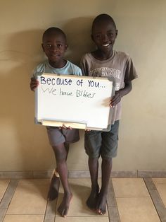 two young boys standing next to each other holding a sign