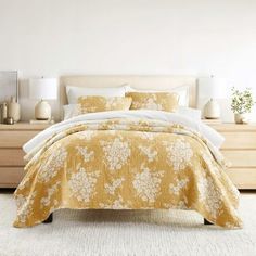 a bed with yellow and white bedspread in a bedroom next to a dresser