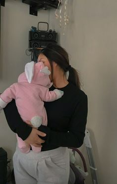 a woman holding a pink stuffed animal in her arms