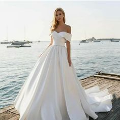 a woman in a white wedding dress standing on a dock