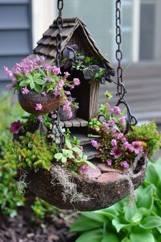 a bird house hanging from a chain filled with flowers