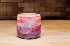 a pink and purple candle sitting on top of a wooden table