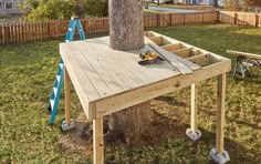 a wooden table sitting under a tree with tools on it