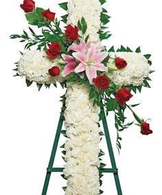 a cross with roses and lilies on it is placed in front of a white background