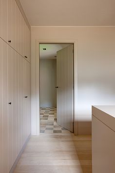 an empty hallway with white cabinets and wood flooring