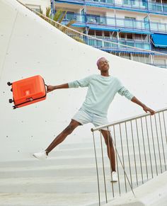 a man with an orange suitcase is standing on some stairs and leaning against the railing