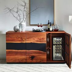 a wooden cabinet with wine bottles and glasses on it