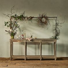 a table with plants and bottles on it in front of a wall mounted planter