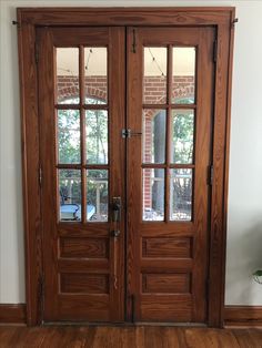 two wooden doors in front of a brick wall and wood flooring with glass panes