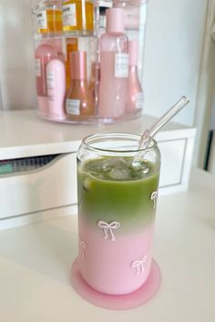 a pink and green drink sitting on top of a white counter next to a shelf