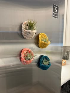 three air plants are hanging on the side of a stainless steel refrigerator in a kitchen