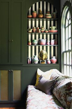 a living room filled with furniture and lots of green cupboards next to a window