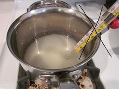 a person is holding a thermometer in front of a saucepan with boiling water