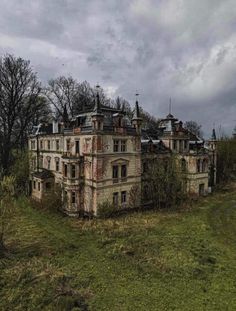 an old abandoned house sitting in the middle of a field with lots of trees around it