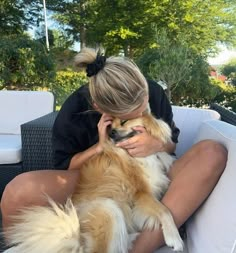 a woman sitting on top of a white couch holding a brown and white dog in her lap